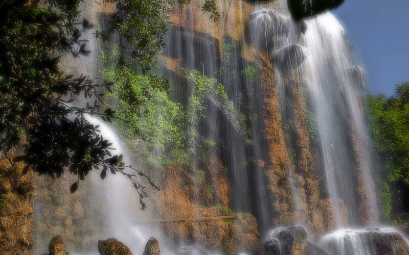 Waterfall on Rocky Cliff — Green, Serene, Afternoon, Photograph, Trees, Rocks, Sky