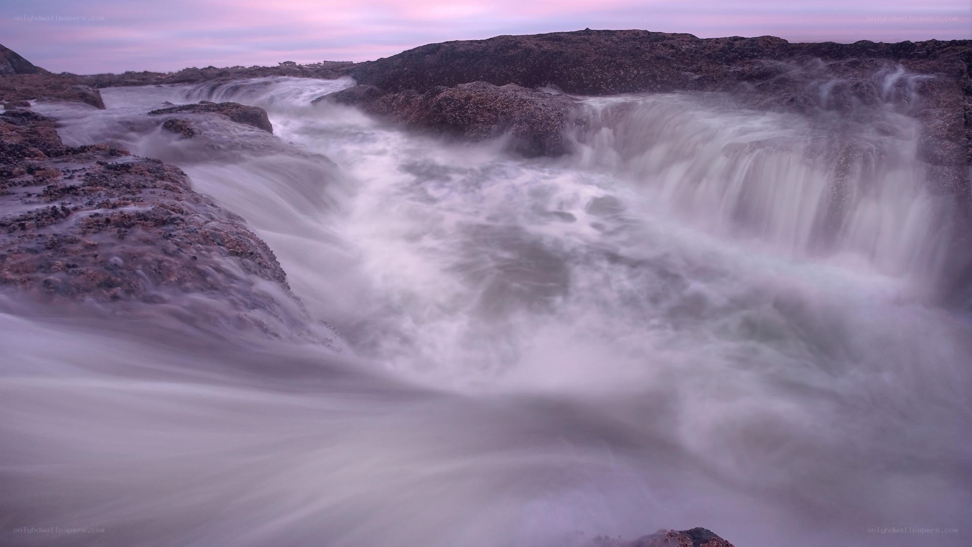 Waterfall on rocky coast at dusk
