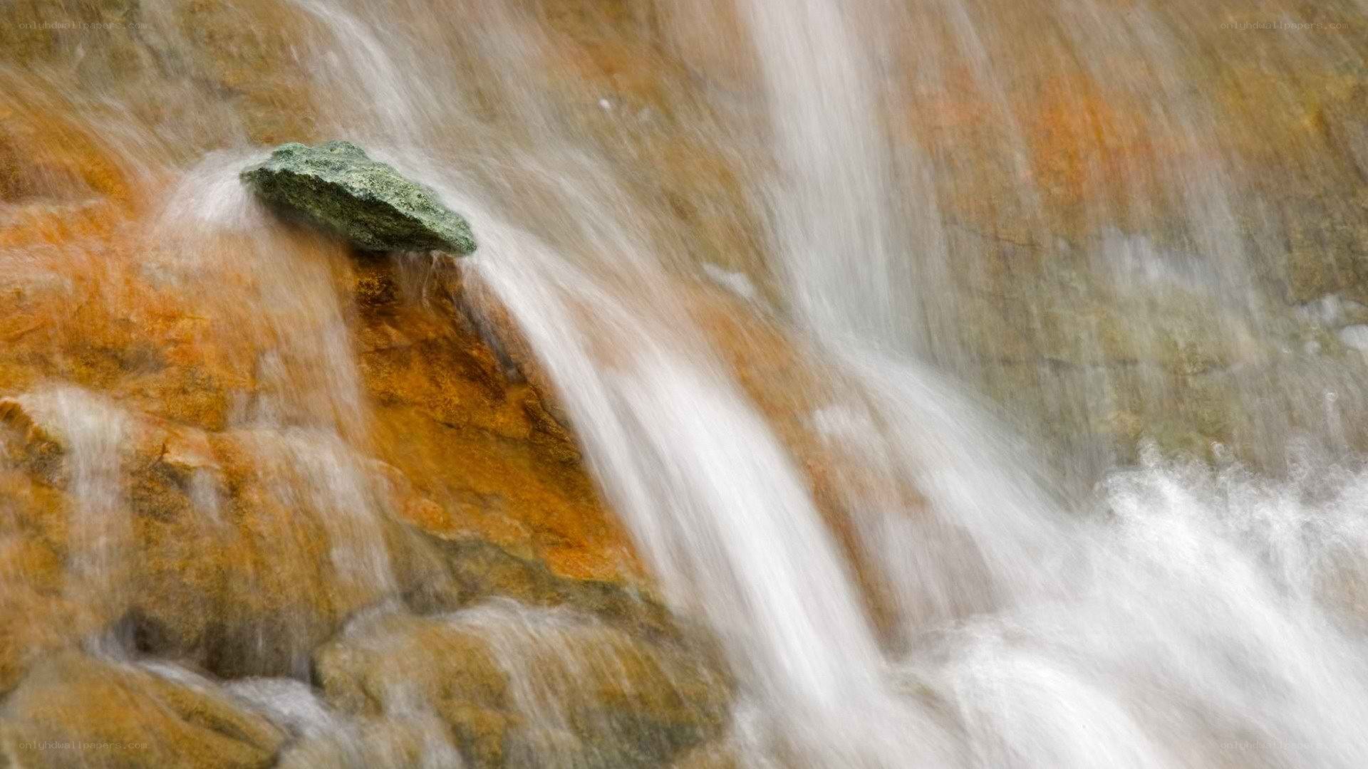 Waterfall over orange rock