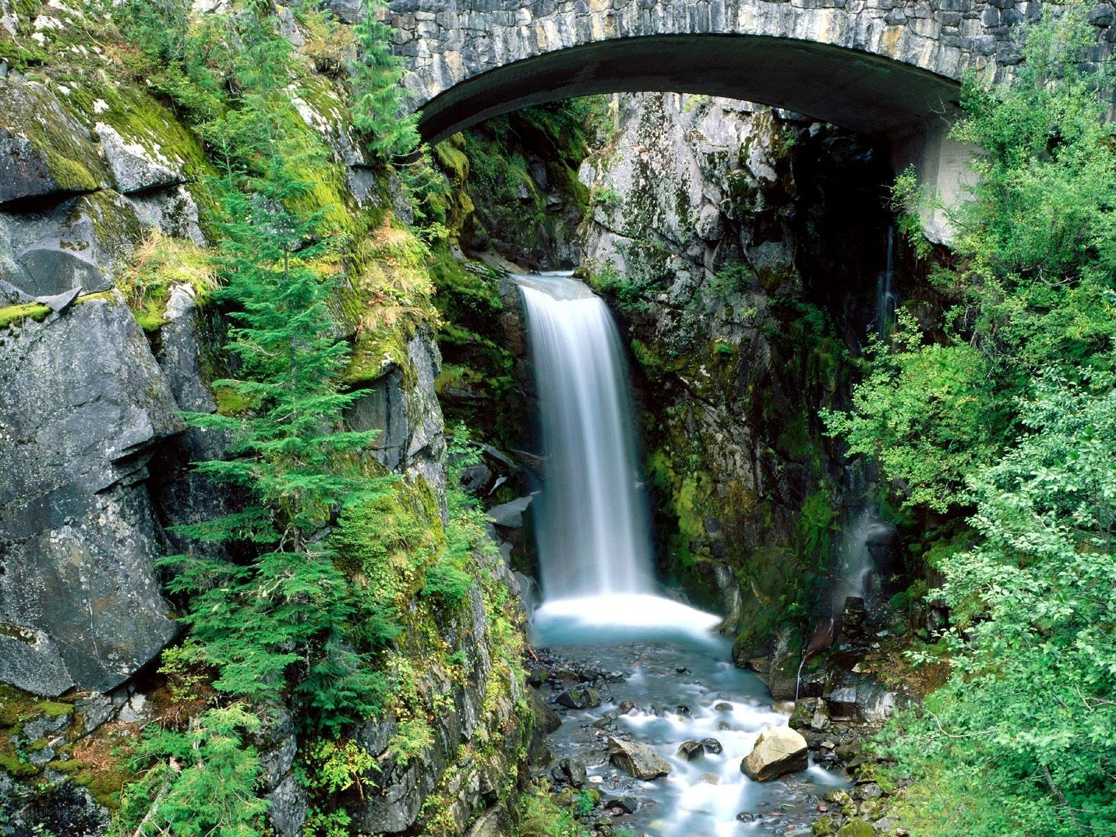 Waterfall under stone bridge