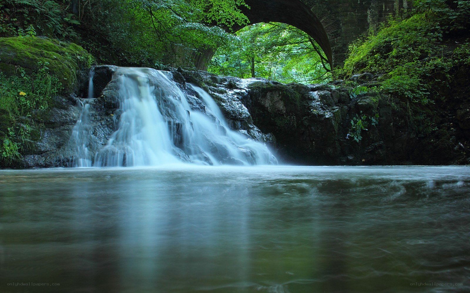 Waterfall under stone bridge