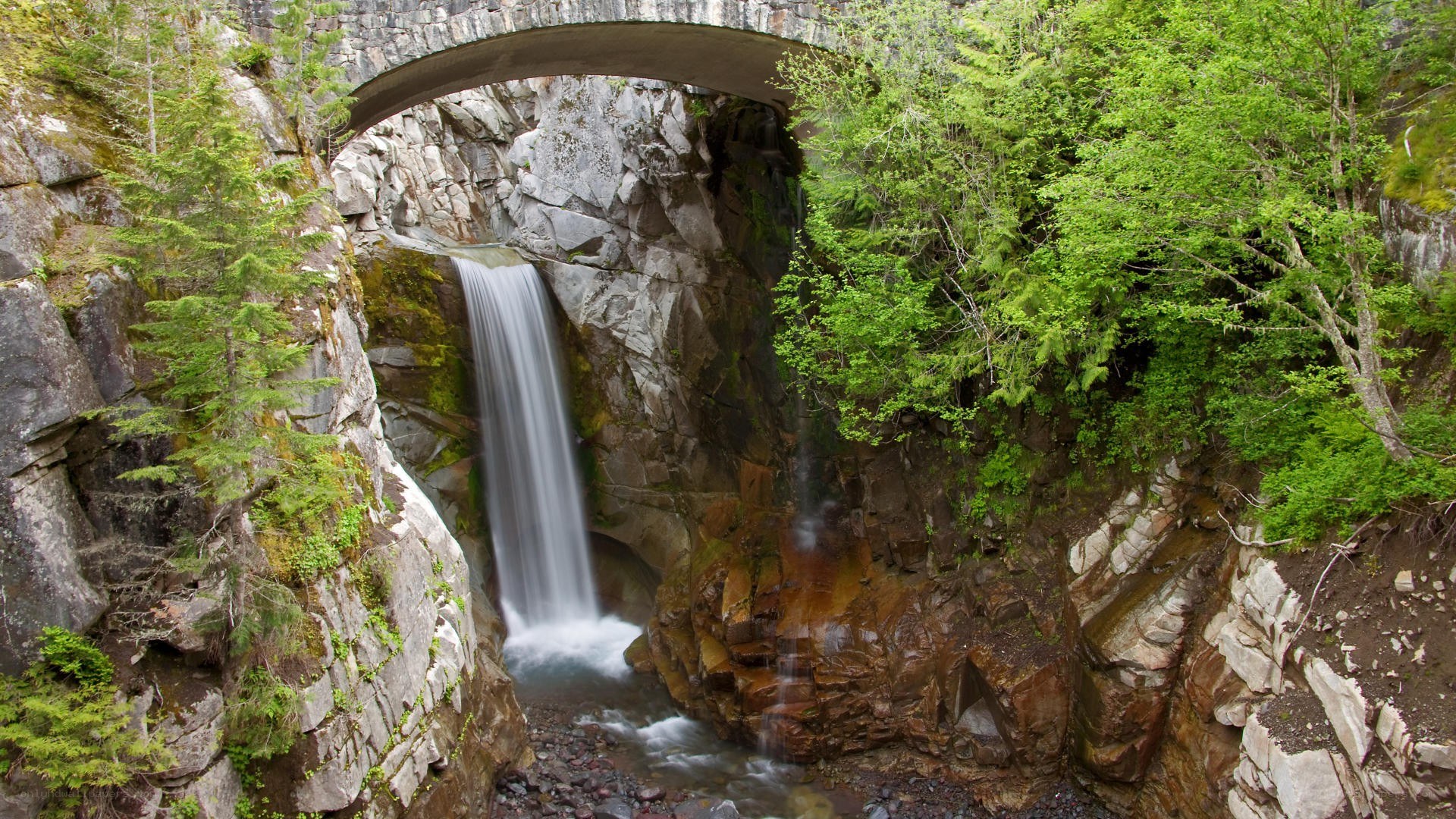 Waterfall under stone bridge