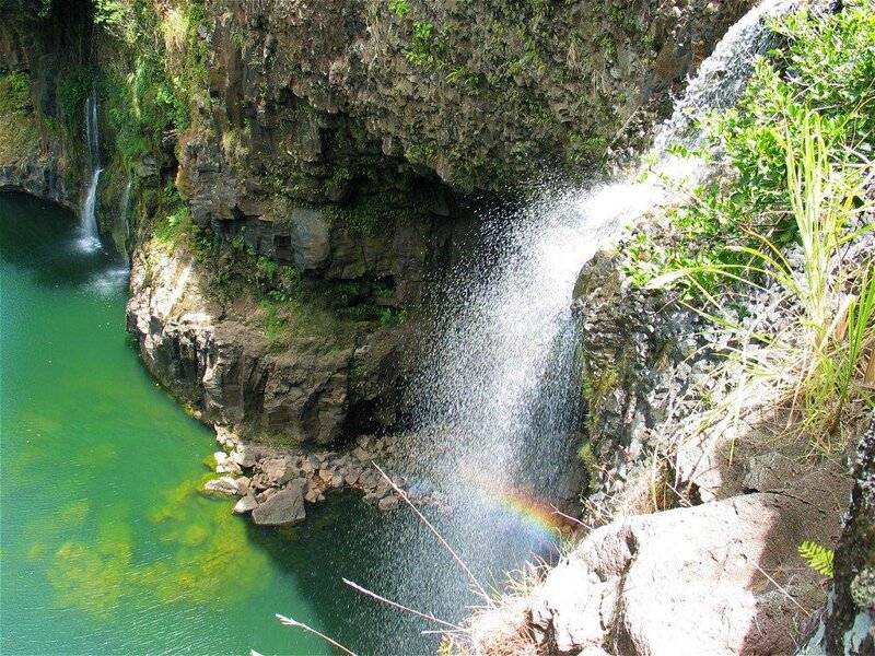Waterfall with rainbow in a green pool