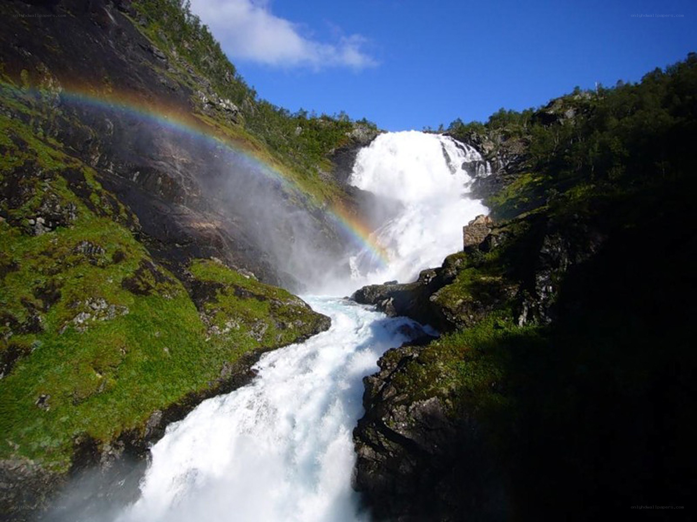 Waterfall with rainbow in canyon