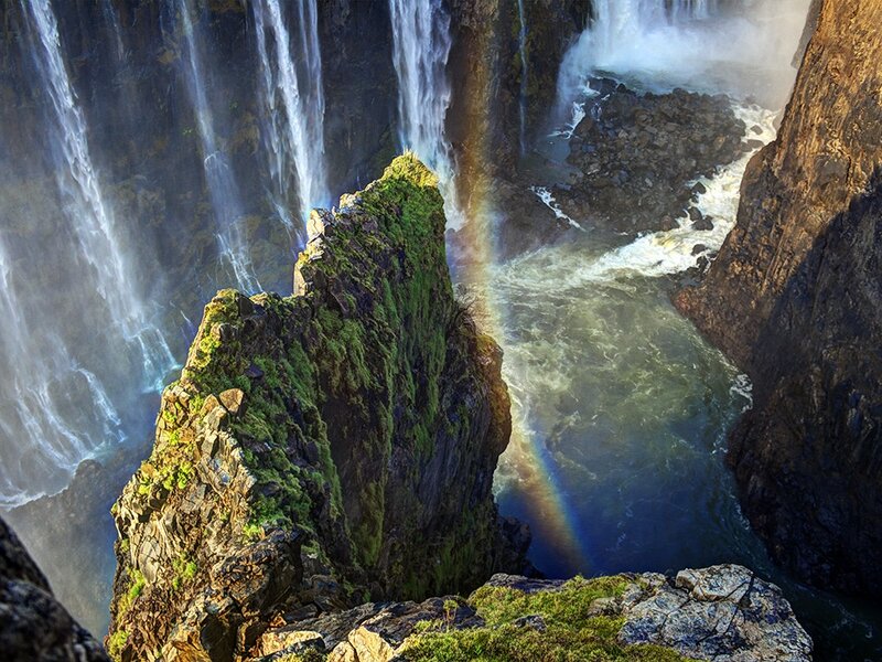 Waterfall with rainbow in canyon