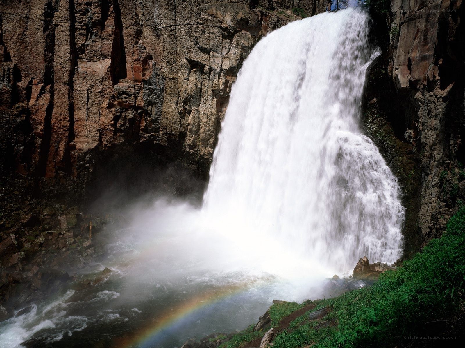 Waterfall with rainbow in canyon