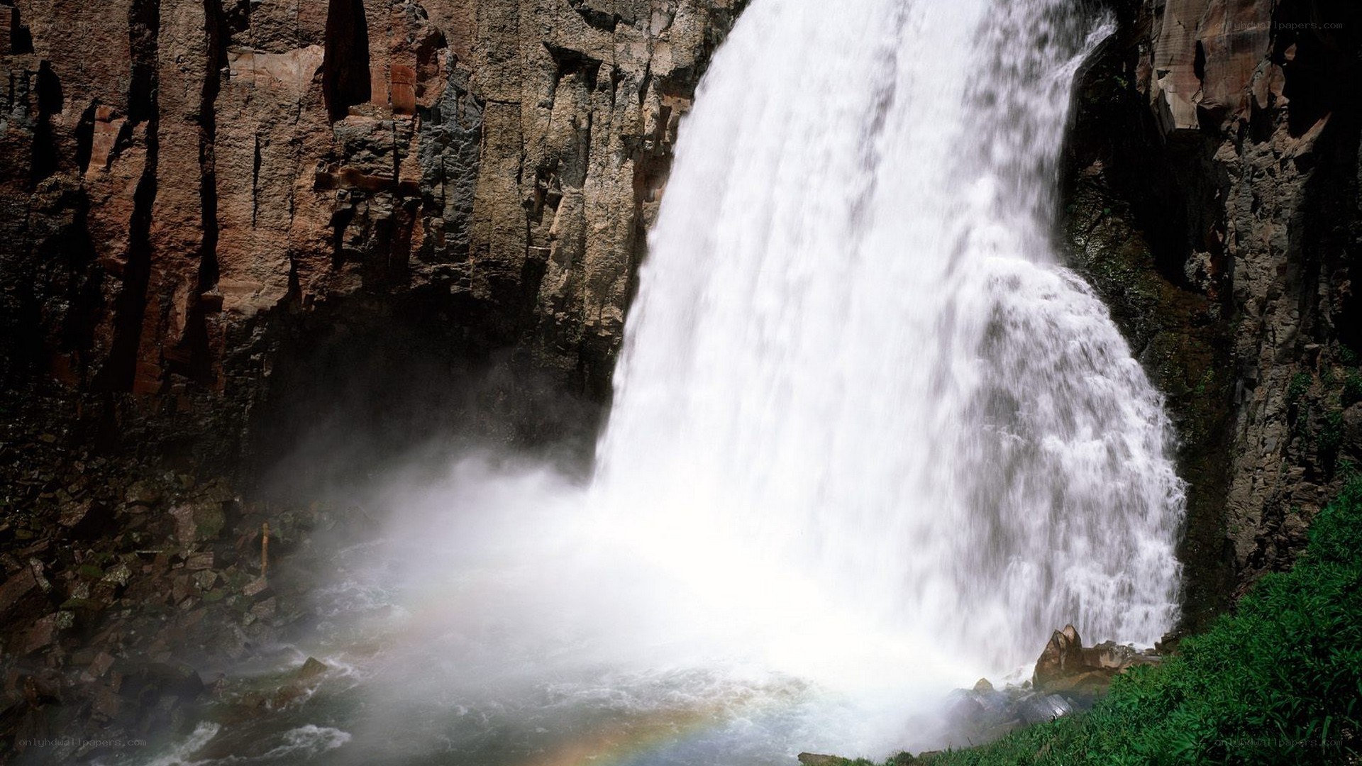 Waterfall with rainbow in canyon