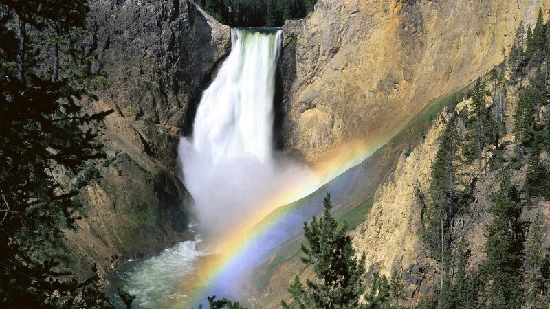 Waterfall with rainbow in canyon