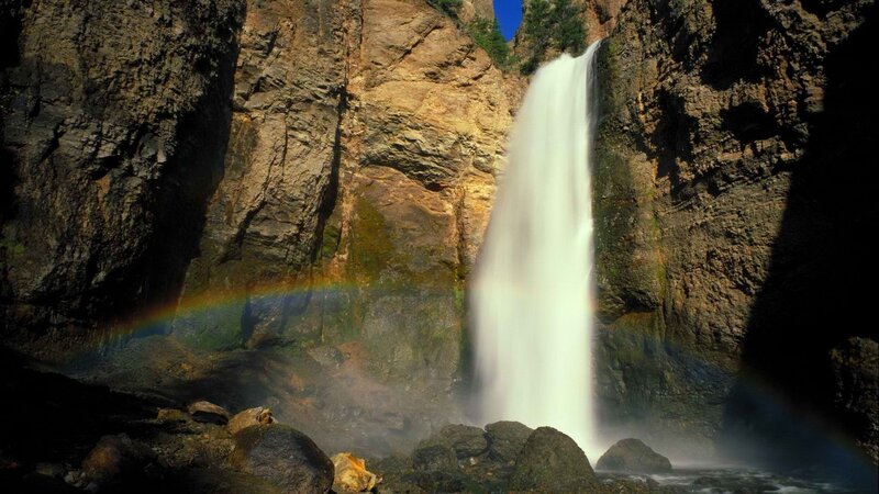 Waterfall with rainbow in canyon