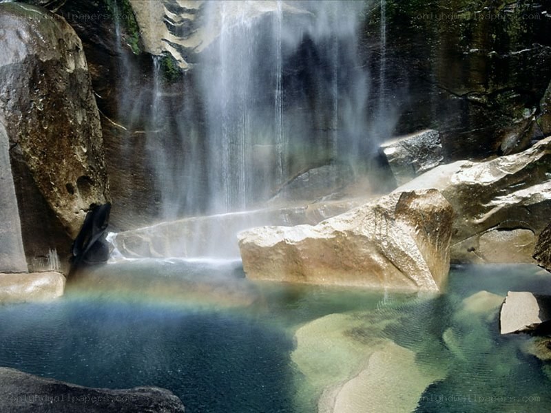 Waterfall with rainbow in pool