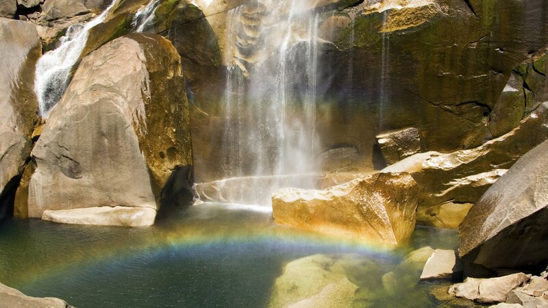 Waterfall with rainbow in pool