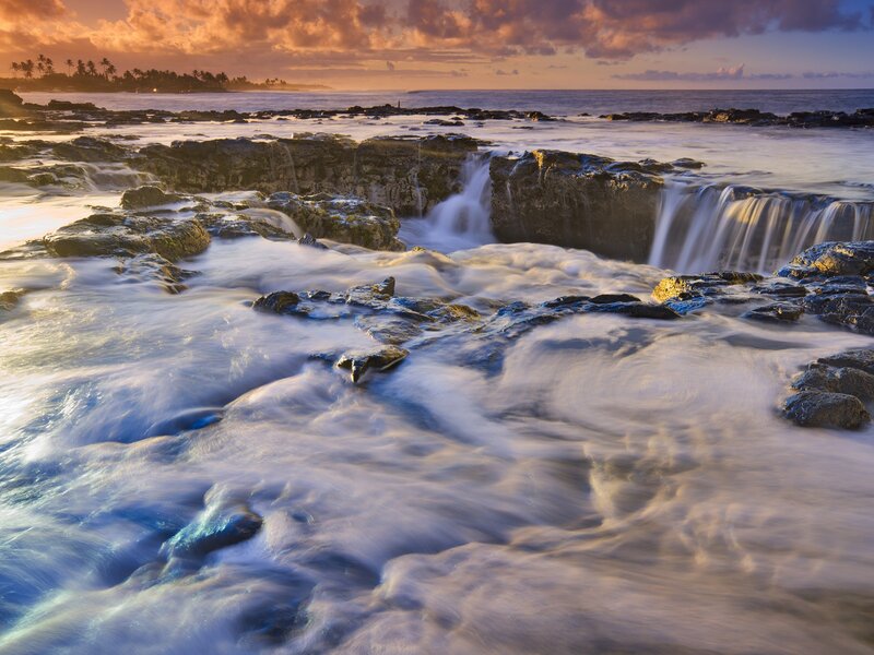 Waterfalls on rocky shore at sunset