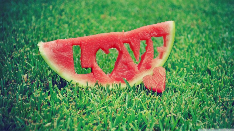 Watermelon slice with 'LOVE' carved on grass