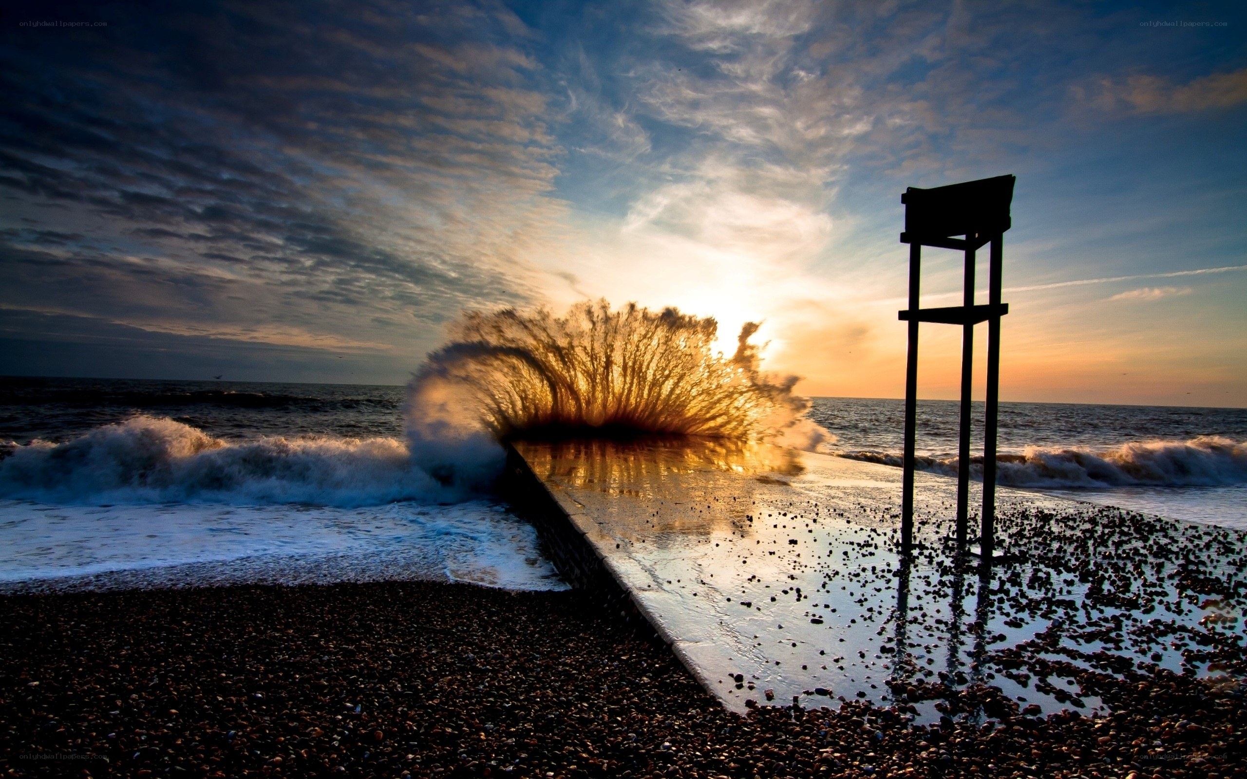Wave crashes on pier at sunset