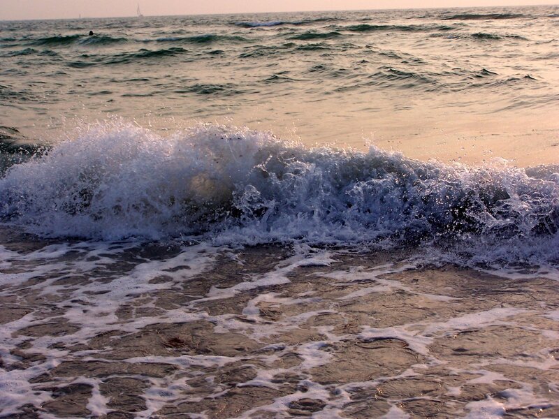 Wave crashing on beach at sunset