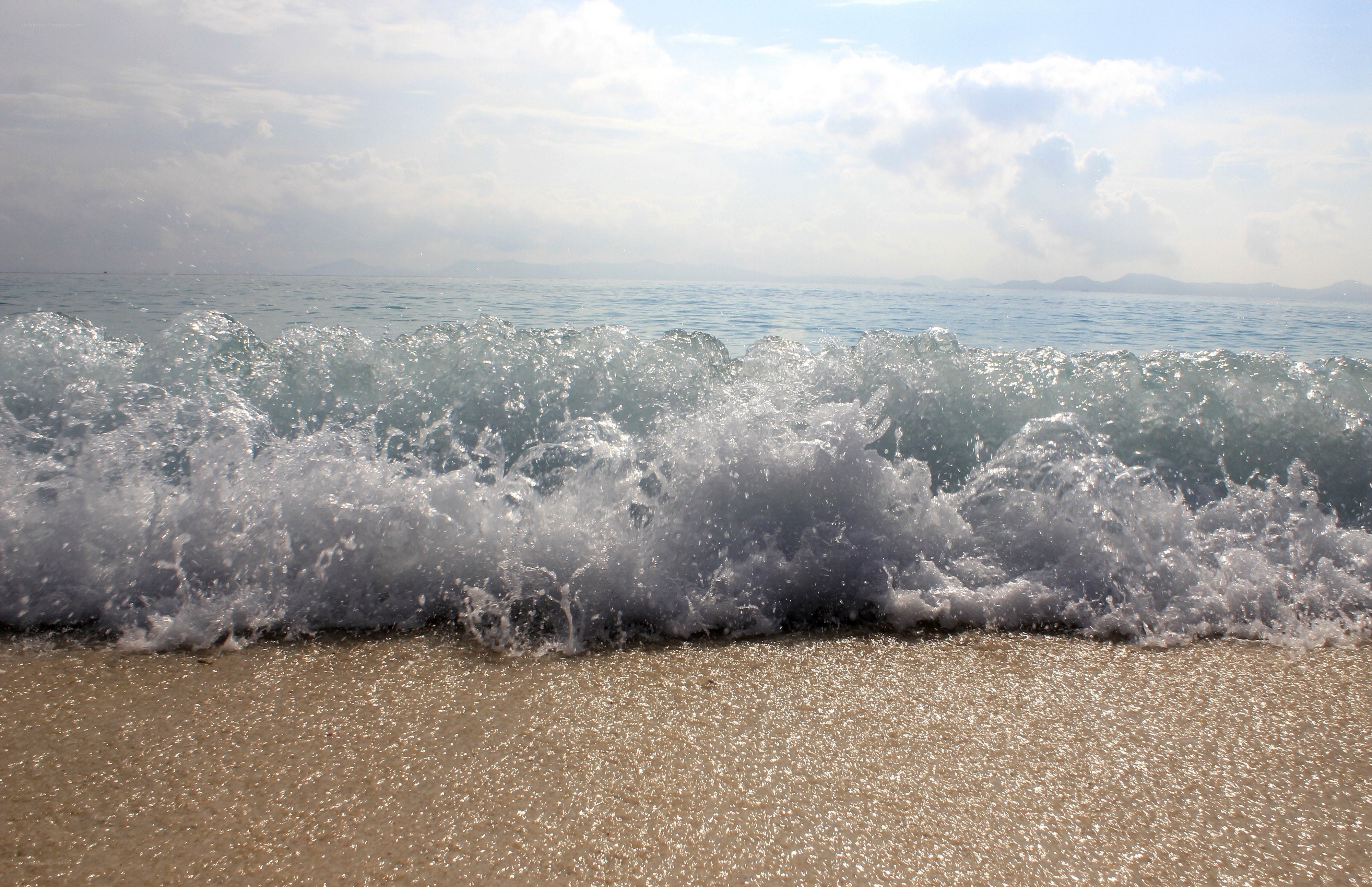 Wave crashing on sandy beach