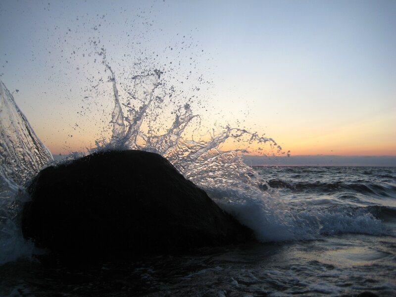 Wave splashing on rock at sunset