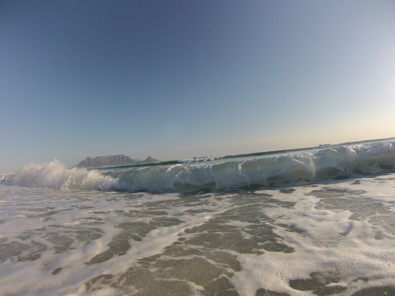 Waves crashing on beach with Table Mountain