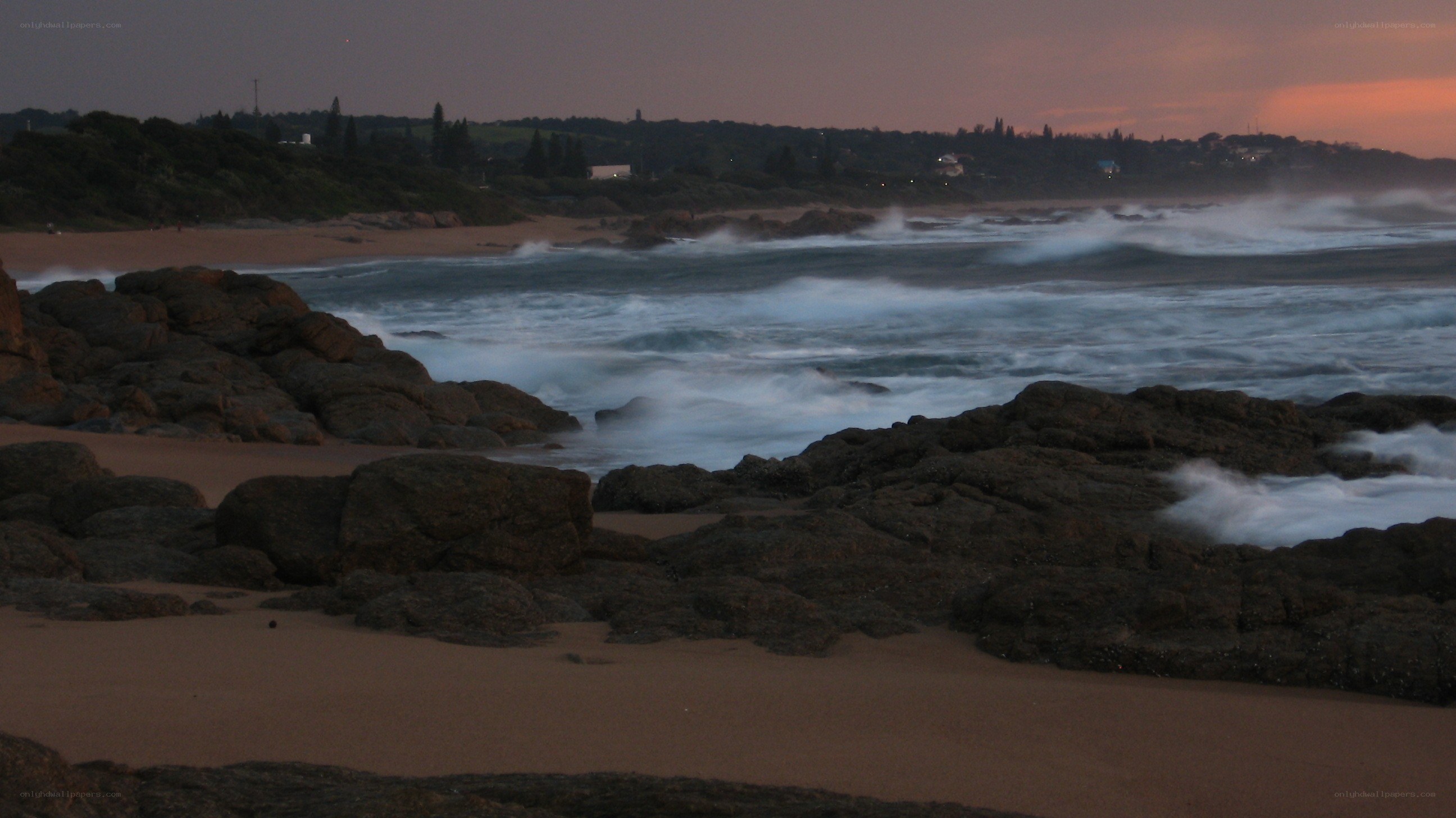 Waves crashing on rocks at dusk