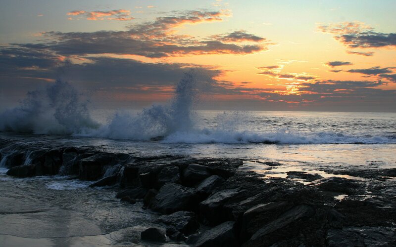Waves crashing on rocks at sunset