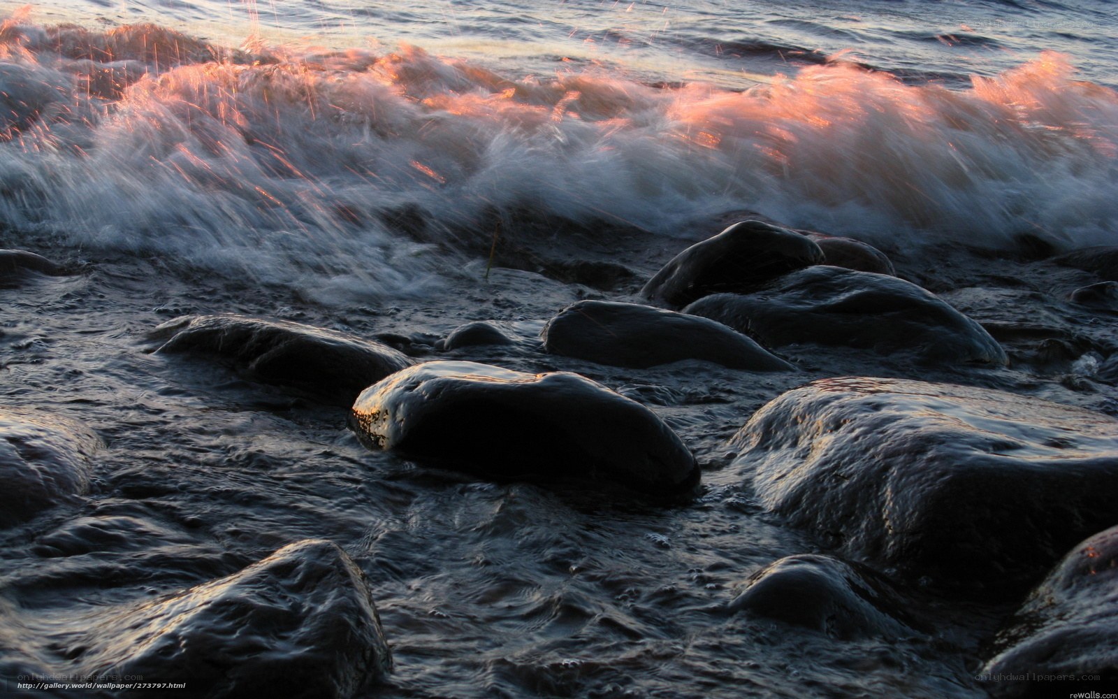 Waves crashing on rocks at sunset
