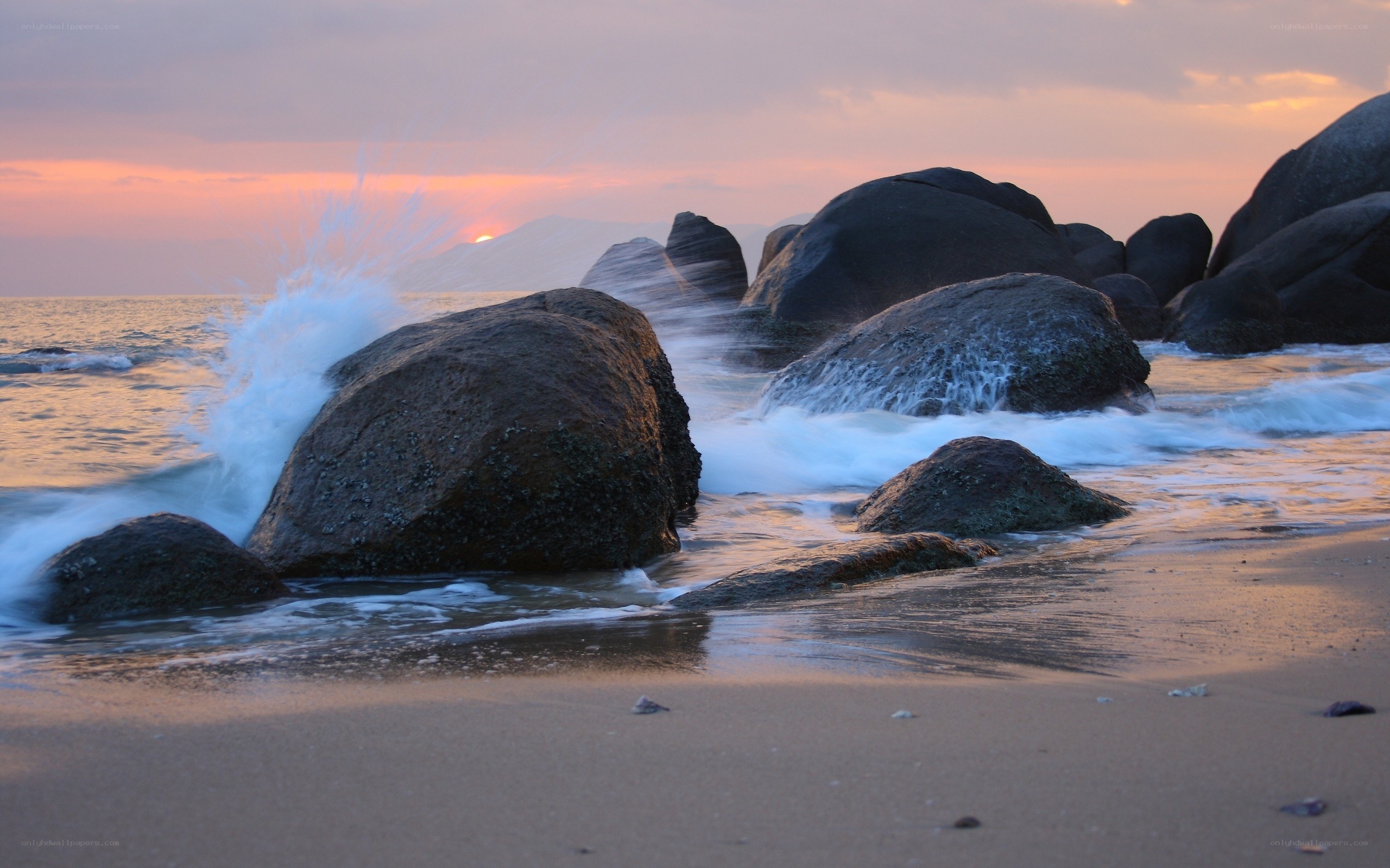 Waves crashing on rocks at sunset