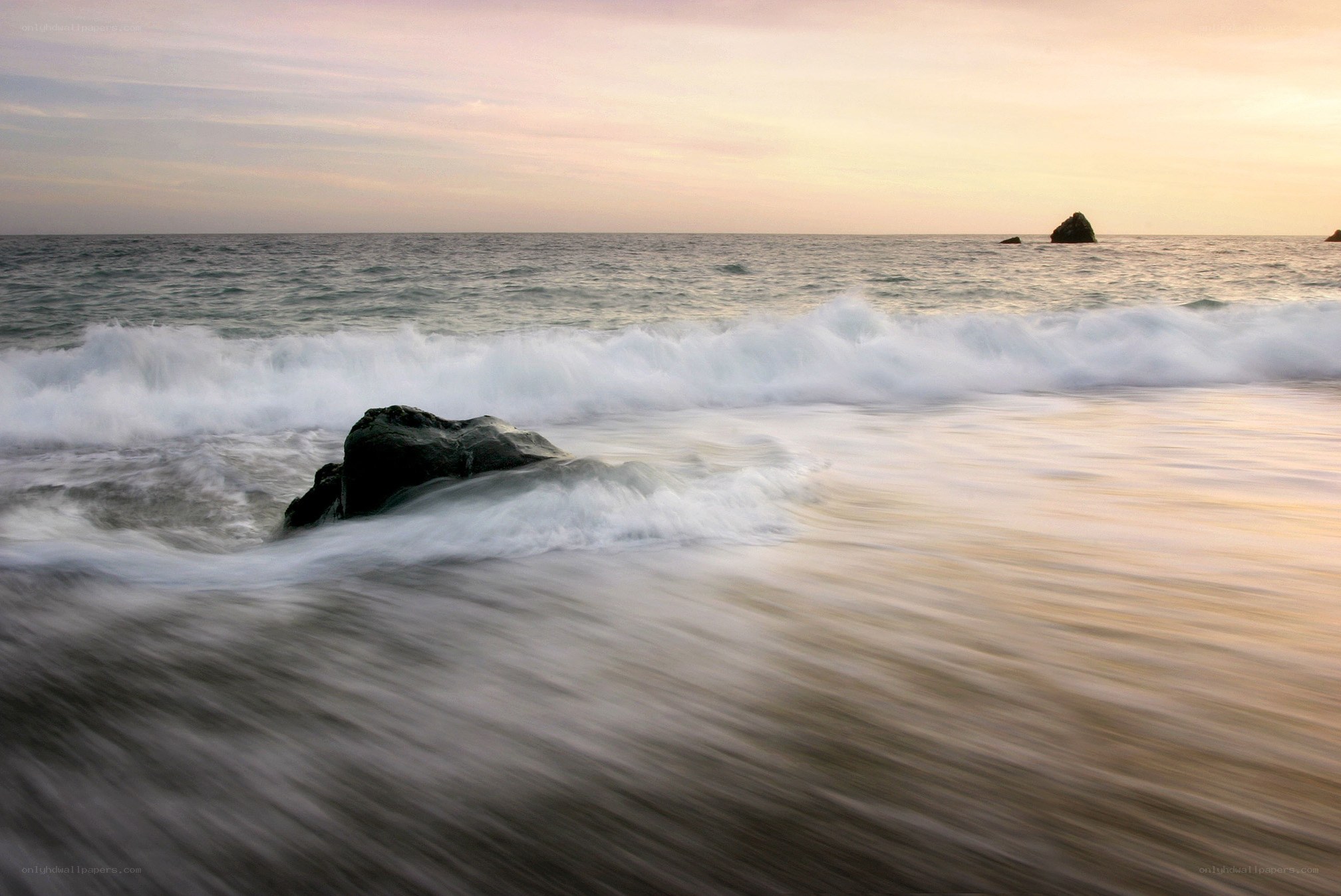 Waves crashing on rocks at sunset