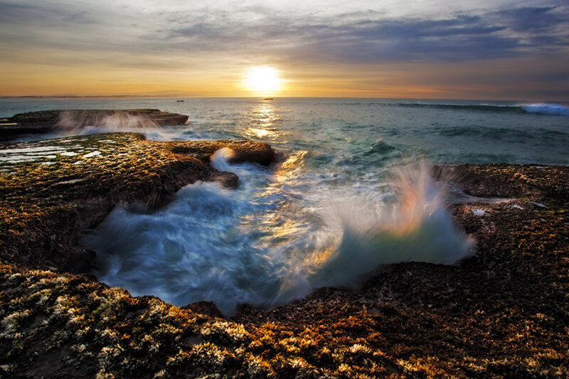 Waves crashing on rocky shore at sunset