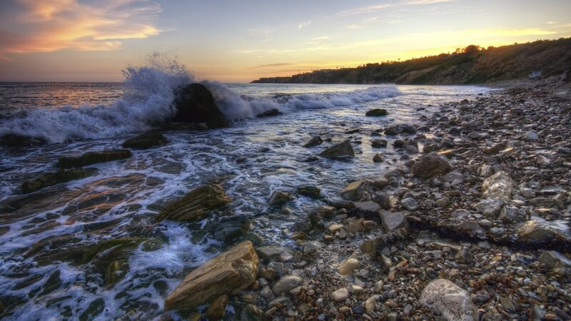 Waves crashing on rocky shore at sunset