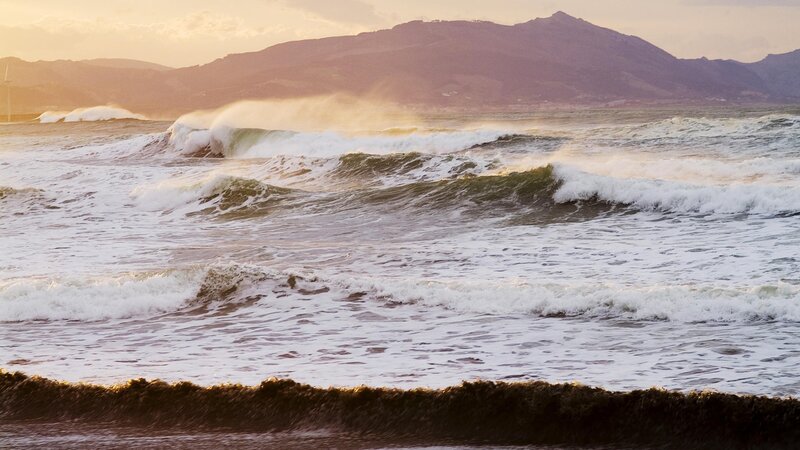 Waves crashing on shore at sunset