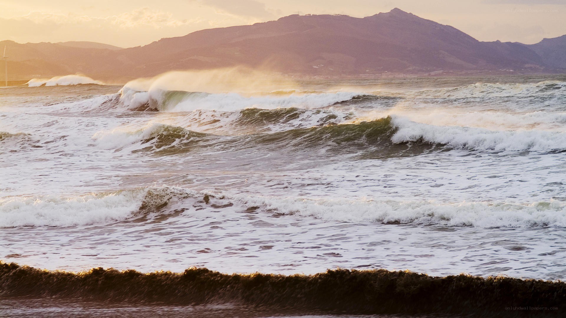 Waves crashing on shore at sunset