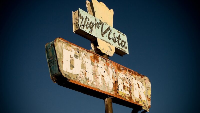 weathered diner sign against blue sky