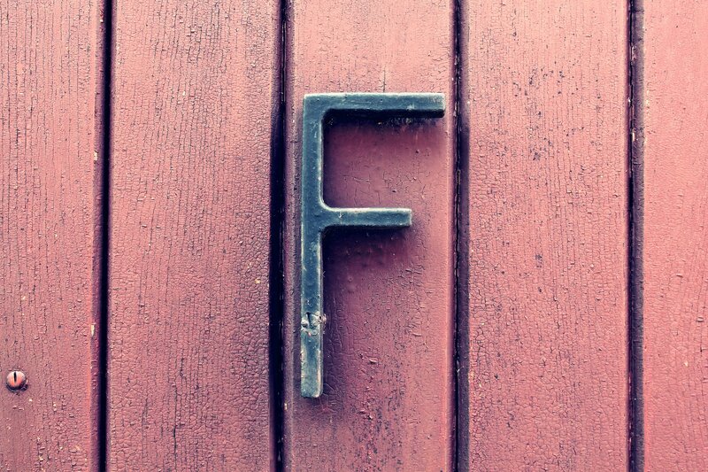 Weathered letter F on red wood