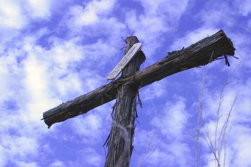 Weathered wooden cross against sky