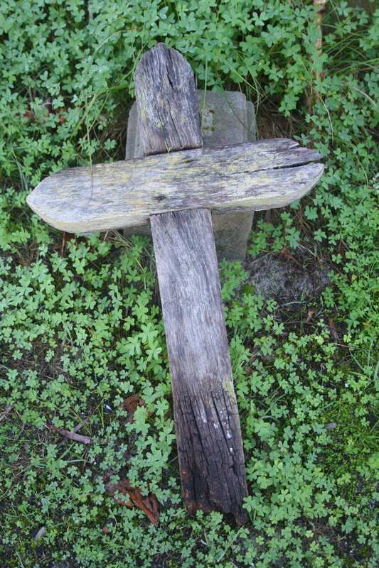 Weathered wooden cross in grass