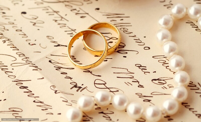 Wedding rings and pearls on letter