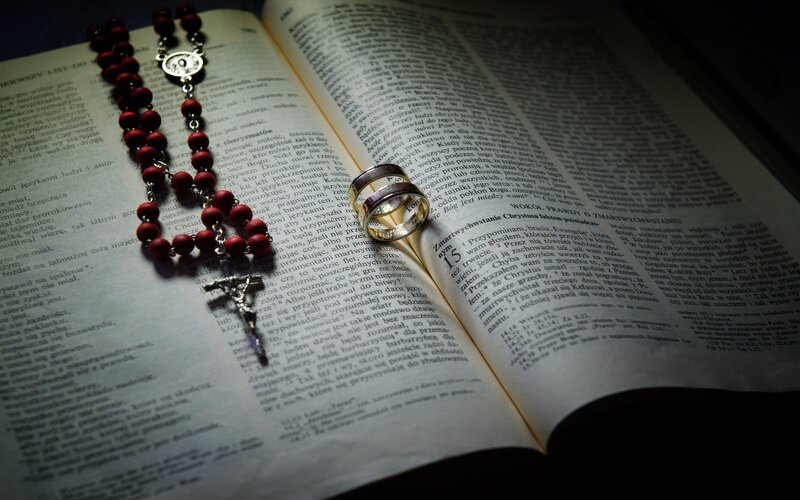 Wedding rings and rosary on a book