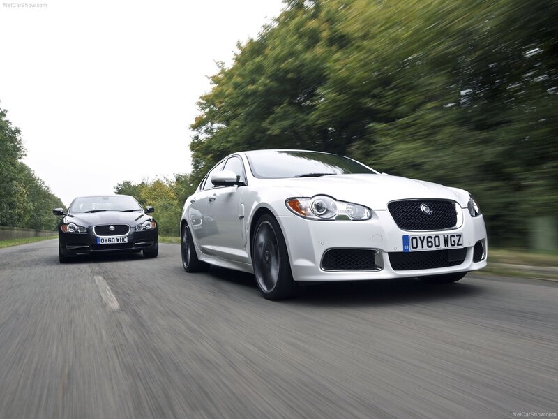White and black Jaguar sedans on road