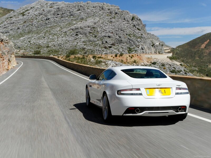 white aston martin driving on mountain road