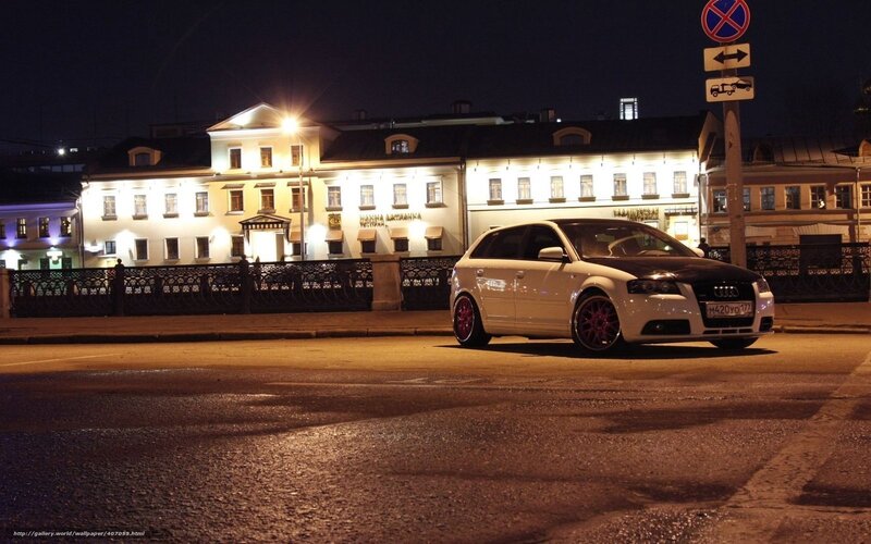 White Audi on city street at night