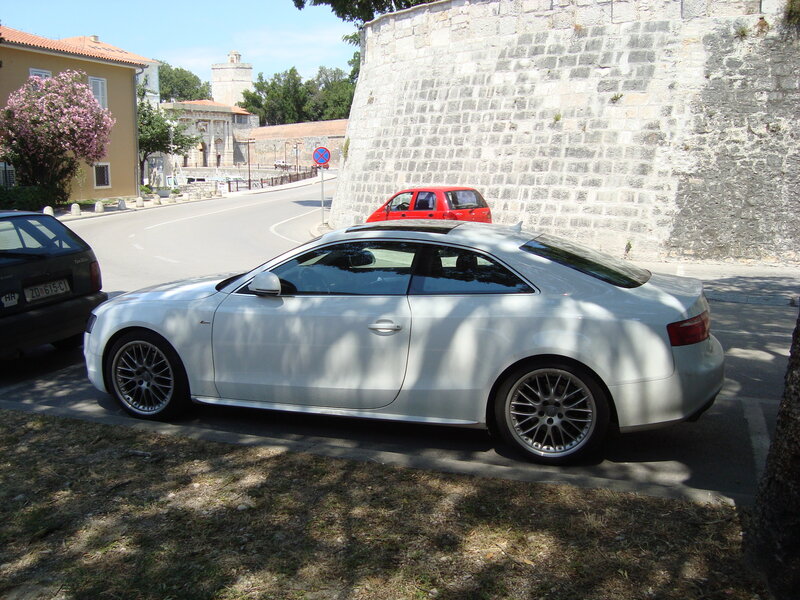 White Audi parked near stone wall