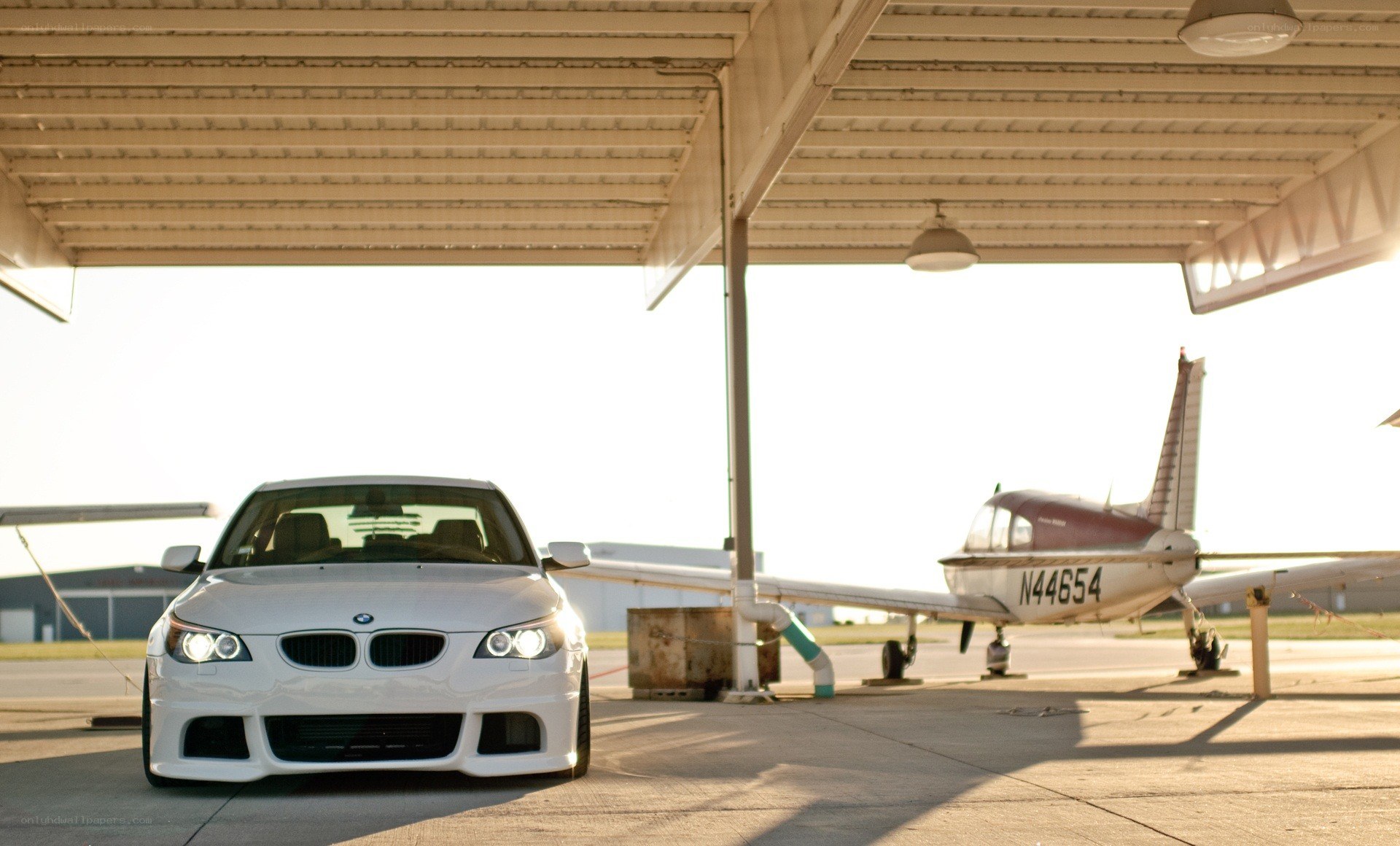 White BMW and small plane at airfield
