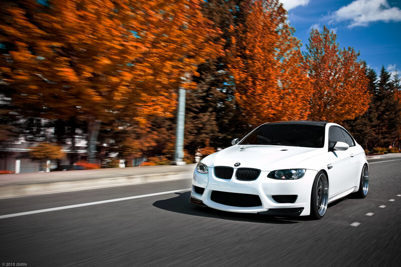 White BMW driving on autumn road