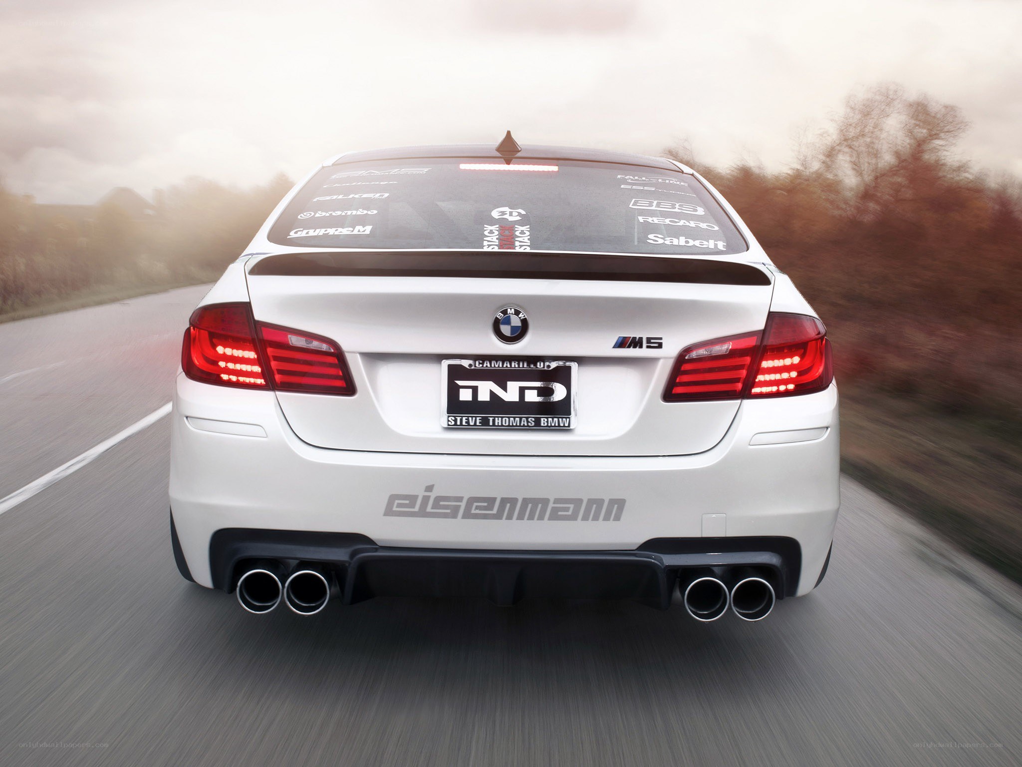white bmw m5 driving on road