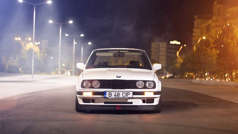 White BMW on city street at night