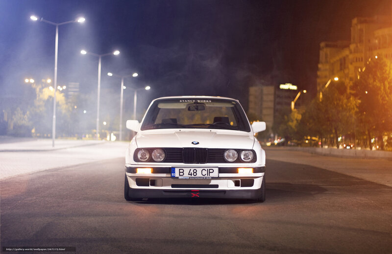 White BMW on city street at night