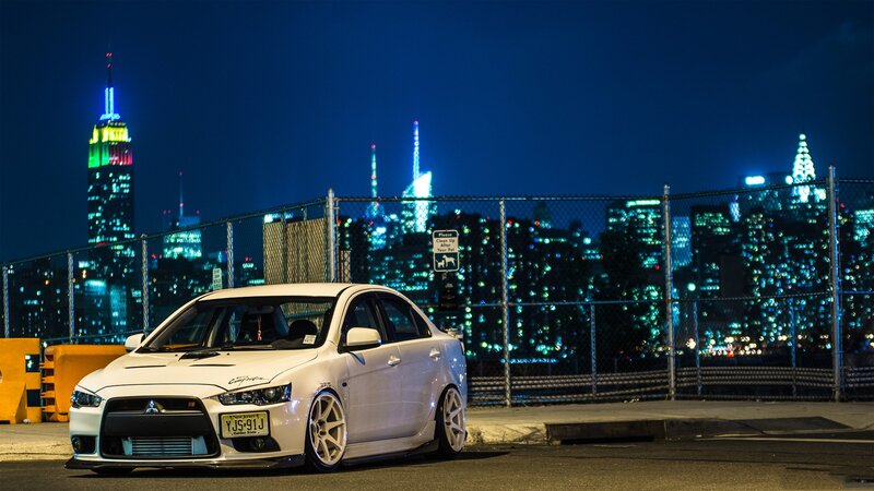 White car at night with city skyline