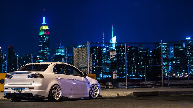 White car at night with city skyline