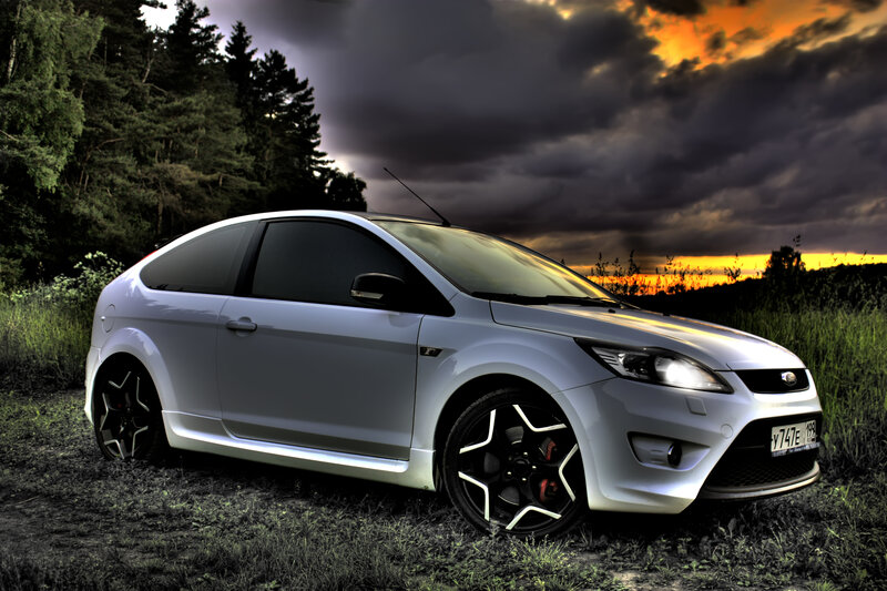 White car in a field at sunset