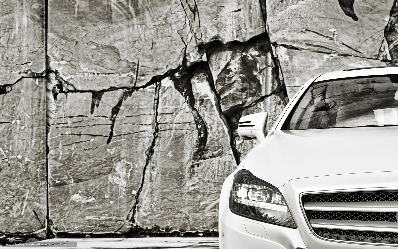 White car in front of rock wall